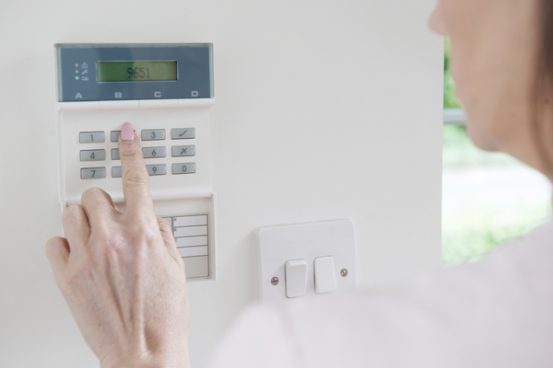 Image of woman pushing the buttons on a home security system.